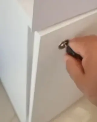 Fechadura instalada em porta de armário, com a chave na mão